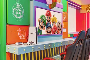 A colorful gaming setup with a screen displaying Mario characters, a gaming chair, and a gaming console. - 10BR house with game room, sleeps 22 in clermont (Clermont)