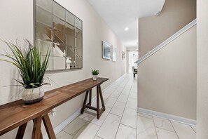 Ein Flur mit einer Holzbank, einem Blumentopf, einem großen Spiegel und einer Treppe.