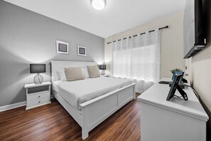 Ein Schlafzimmer mit einem Bett, Nachttischen, einem Schreibtisch und einem Fernseher.