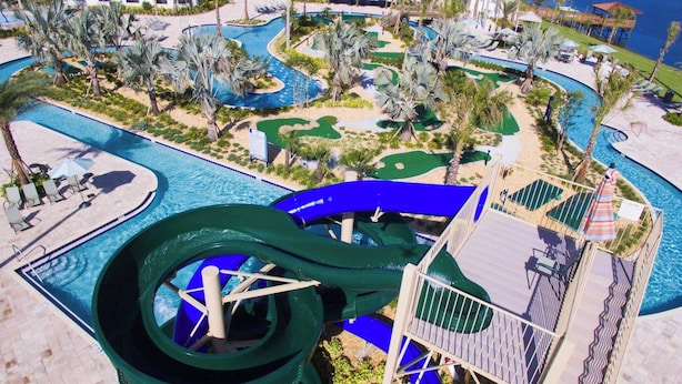 Un resort con un tobogán acuático grande, varias piscinas y un campo de golf.
