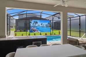 A poolside area with a glass enclosure, outdoor seating, and a Samsung refrigerator. - 8BR house sleeps 22 near Disney area (Clermont)