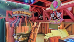 Ein Raum im Mickey & Minnie Stil mit einem Schild, einer Mickey Mouse Figur, einer Leiter und einem Bett.