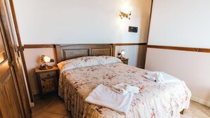 A bedroom with a floral bedspread, a wooden headboard, bedside lamps, and a nightstand with a lamp.