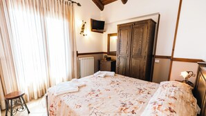 A bedroom with a bed, a wooden wardrobe, a radiator, a television, and a small table. - Agriturismo la Baita  (Agerola)