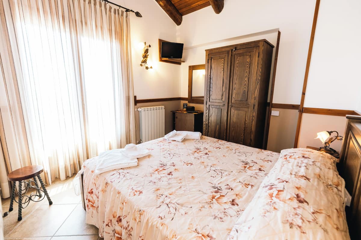 Ein Schlafzimmer mit Bett, einem Holzschrank, einem Heizkörper, einem Fernseher und einem kleinen Tisch.