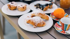 A table with plates of pastries, a bowl of cream, and a glass of orange juice.