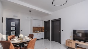 Una sala moderna con comedor, cocina y televisor.