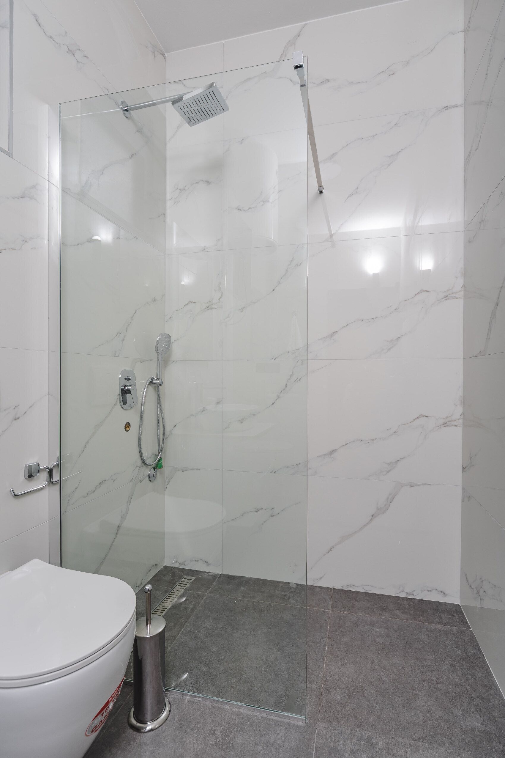 A modern bathroom with a glass-enclosed shower, a toilet, and a bidet.