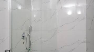 A modern bathroom with a glass-enclosed shower, a toilet, and a bidet.