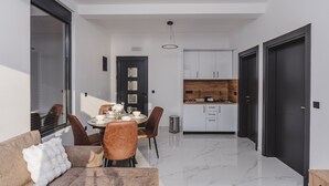 Un interior moderno con comedor, cocina y un sofá con cojín blanco.