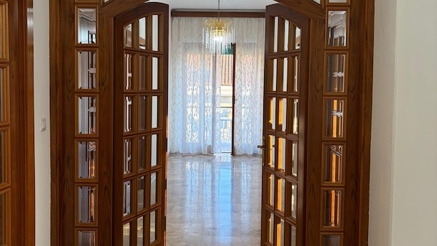Un couloir avec des portes en bois et un lustre.