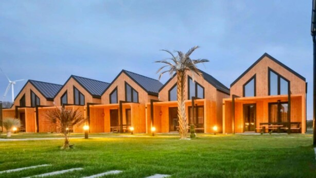 A modern building with multiple rooms, a well-maintained lawn, and a palm tree.