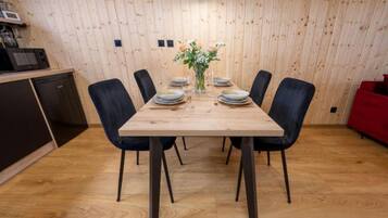 Un coin repas avec une table en bois dressée pour six personnes, entourée de chaises noires.