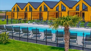 A modern building with a pool and sun loungers.