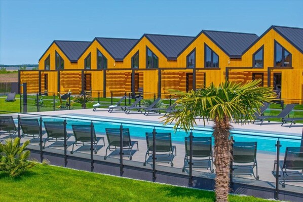 A modern building with a pool and sun loungers.
