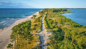 Trilho costeiro com praia e áreas arborizadas.