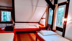 Alojamento em tenda com duas camas, piso de madeira e janelas com cortinas.