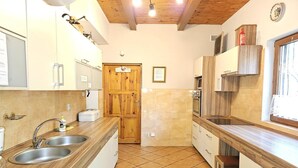 A kitchen with wooden cabinets, a double sink, a stove, and a window. - Holiday villa with sauna, close to the lake (Nowa Kaletka)