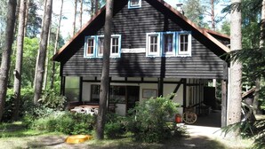 A wooden house with a gabled roof, multiple windows, and a visible garage entrance. - Holiday villa with sauna, close to the lake (Nowa Kaletka)