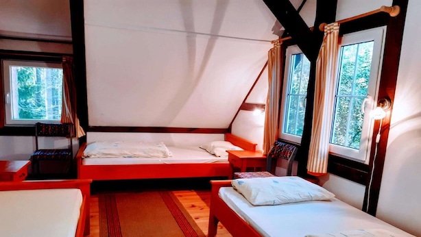 A tented accommodation with two beds, a wooden floor, and windows with curtains. - Holiday villa with sauna, close to the lake (Nowa Kaletka)