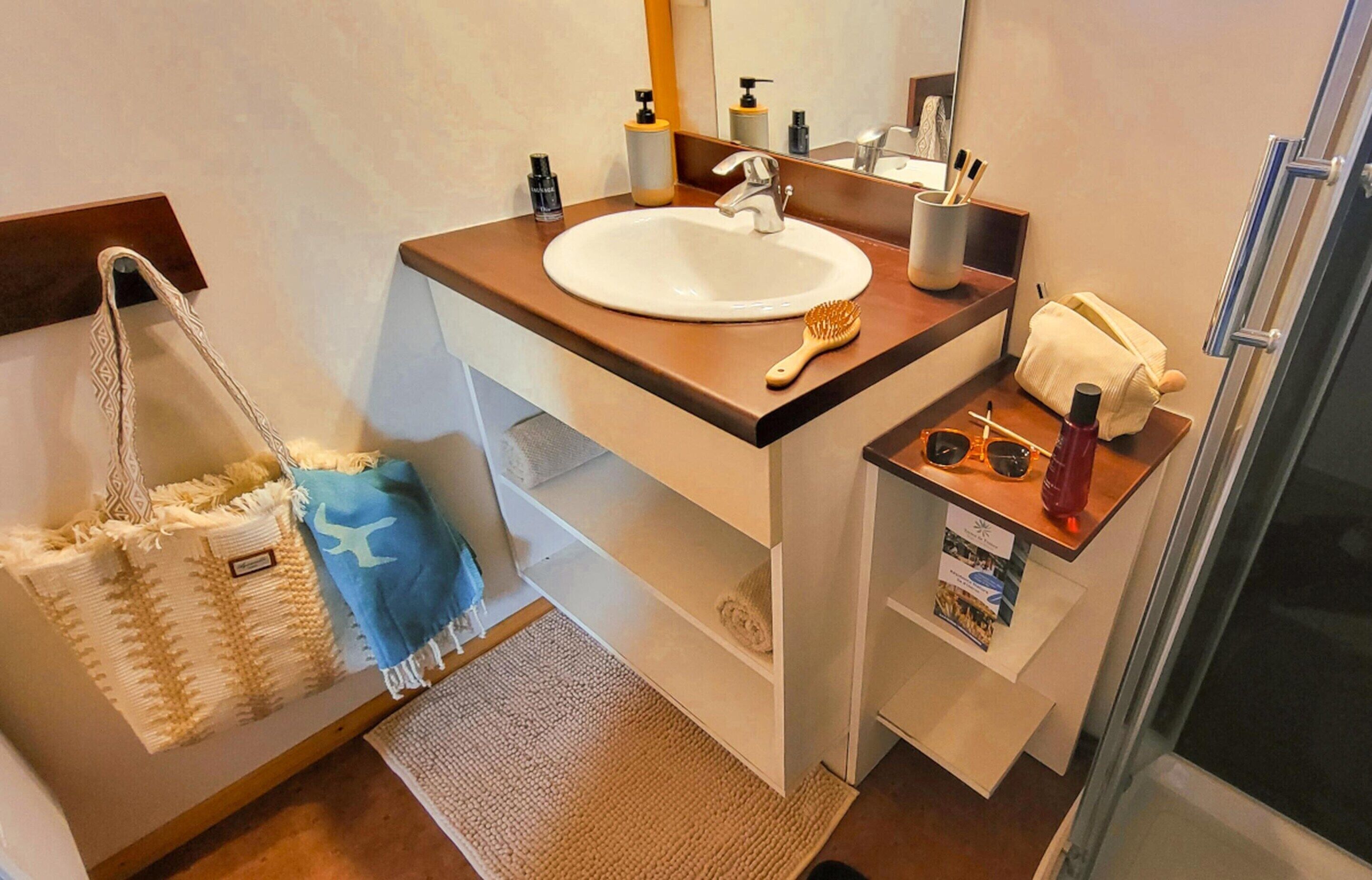 A bathroom with a sink, mirror, towel rack, and a shower area.