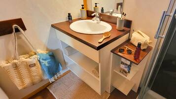 A bathroom with a sink, mirror, towel rack, and a shower area.