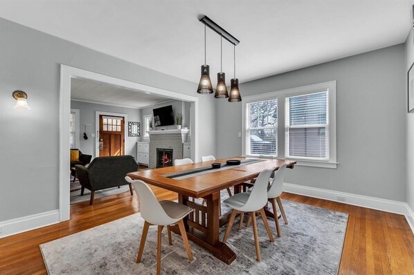 A dining area with a wooden table, four chairs, and hanging pendant lights.