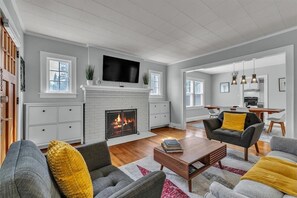 Una sala de estar con chimenea, televisor y comedor con sillas y mesa.