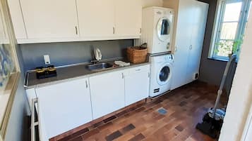 Un área de lavandería con dos lavadoras, un lavabo y una ventana con vistas.