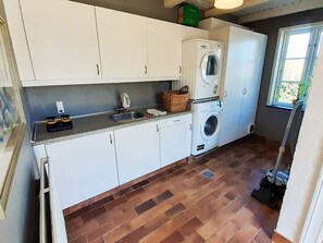 Un área de lavandería con dos lavadoras, un lavabo y una ventana con vistas.