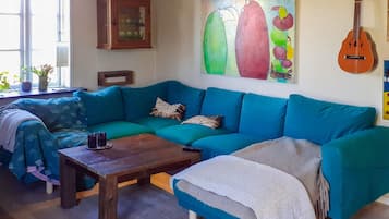 Una sala de estar con un sofá verde azulado, una mesa de centro de madera y un cuadro en la pared.