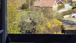 Paisaje rural con una casa, árboles y un camino.