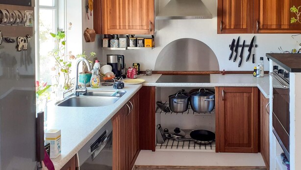 Una cocina compacta con gabinetes de madera, una campana extractora de acero inoxidable y un horno empotrado.