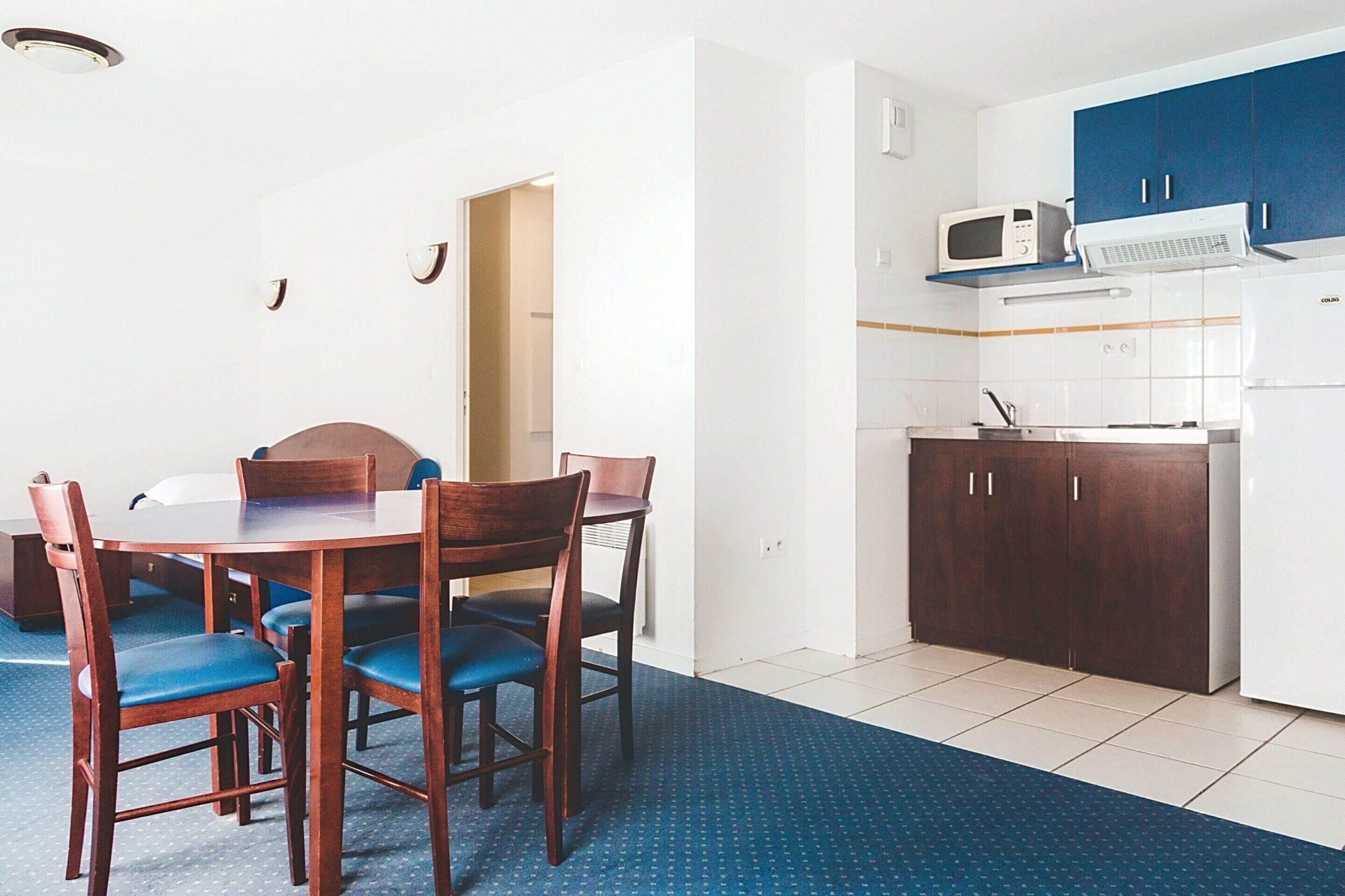 A compact kitchen with white cabinets, a microwave, and a refrigerator.