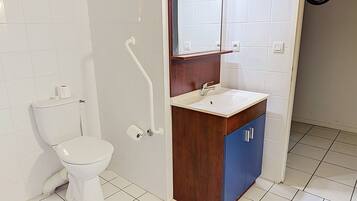A bathroom with a toilet, sink, mirror, and tiled walls.