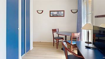 Ein Zimmer mit einem Esstisch, Stühlen, einer Lampe und einem gerahmten Bild an der Wand.