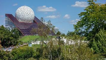 A modern building with a large spherical structure, a sloped roof, and a green lawn.