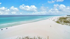 Ein Strand mit blauem Himmel, ruhiger See und einigen Spaziergängern.