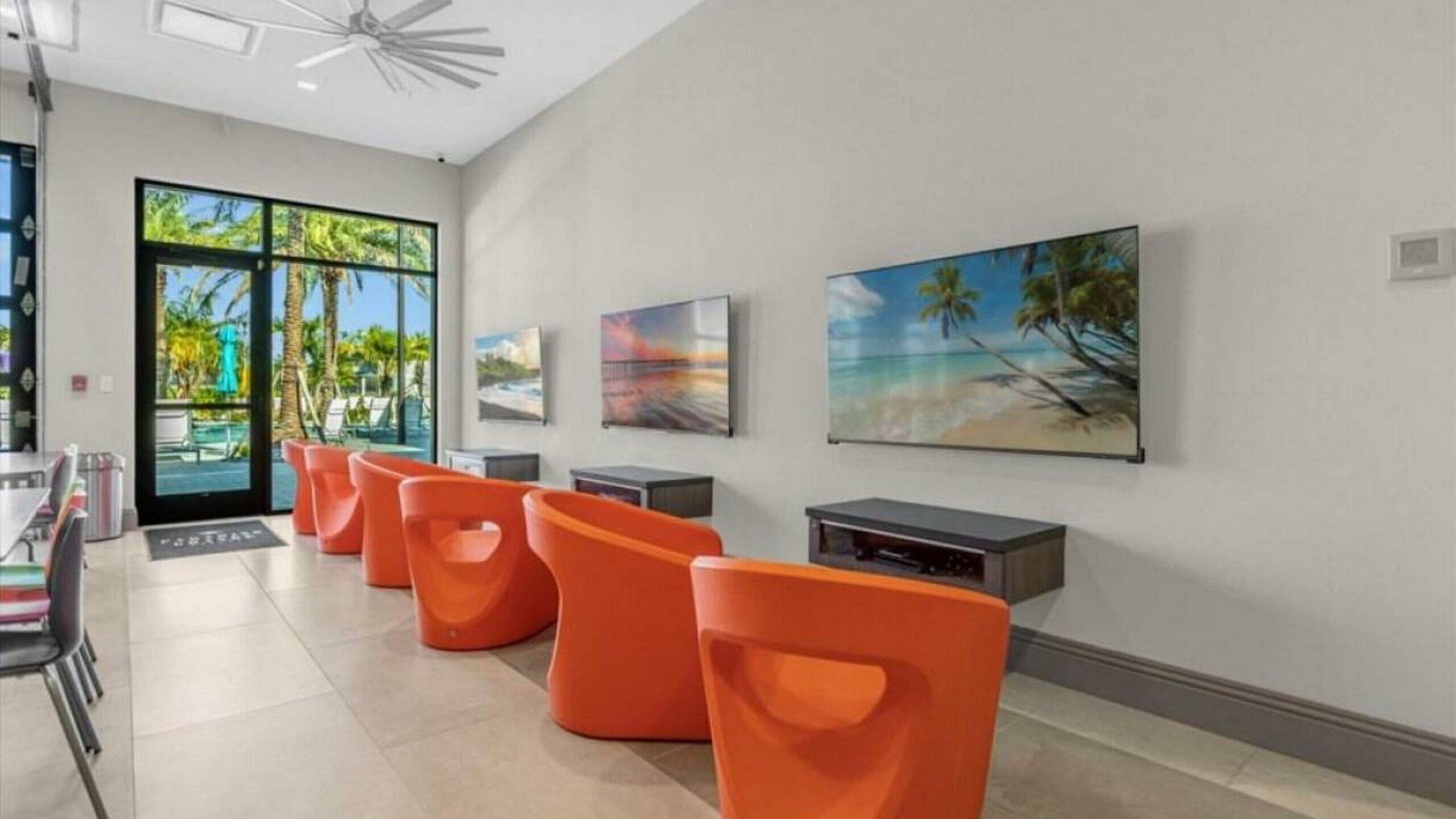 A modern hotel lobby with orange seating, large windows, and artwork on the walls.