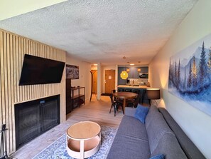 Una sala moderna con una televisión de pantalla plana, chimenea, una mesa redonda, un sofá y un comedor con sillas.
