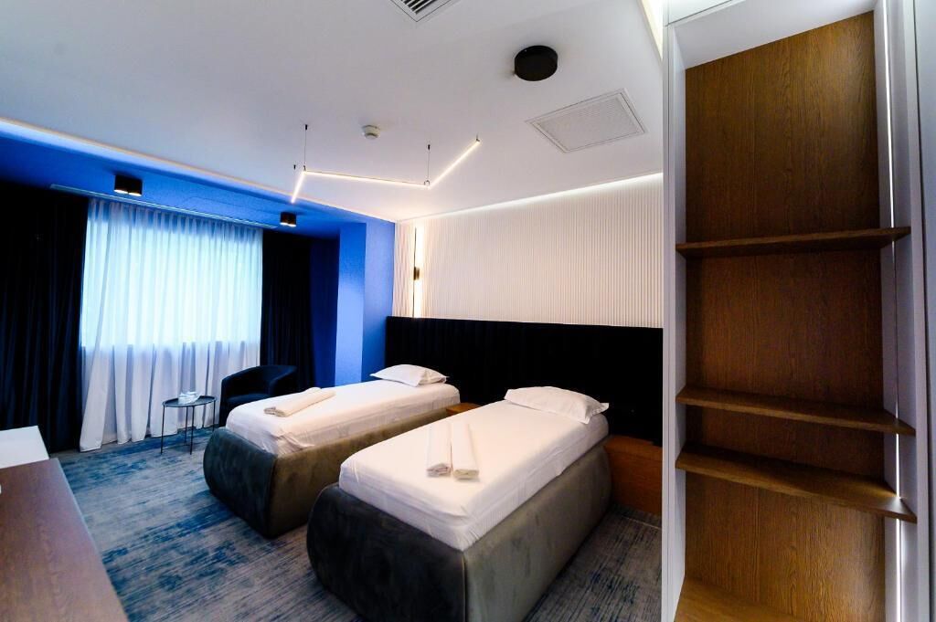 Una habitación de hotel con dos camas, un escritorio, una silla y un armario.
