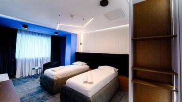 Una habitación de hotel con dos camas, un escritorio, una silla y un armario.