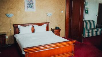 A hotel room with a wooden bed, a nightstand, a lamp, and a chair.