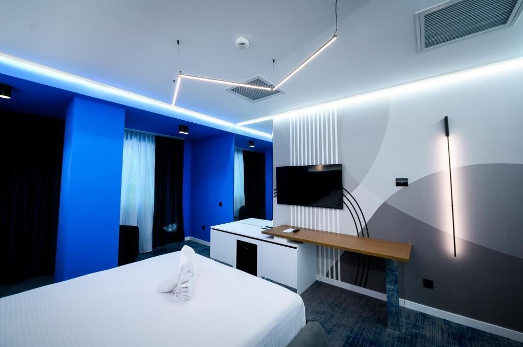 Una habitación de hotel moderna con cama, escritorio y televisión.