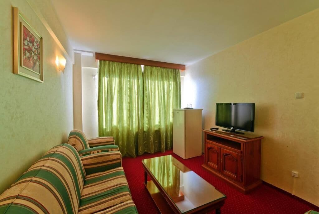 A room with a sofa, a television, a cabinet, and a refrigerator.