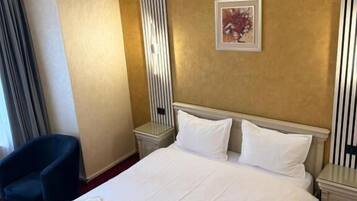 Ein Hotelzimmer mit einem großen Bett, zwei Nachttischen, einem Sessel und einem Kunstwerk an der Wand.