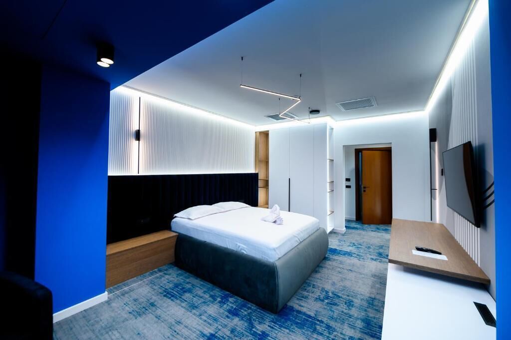 Habitación de hotel moderna con una cama, un escritorio, un televisor y un vestidor.