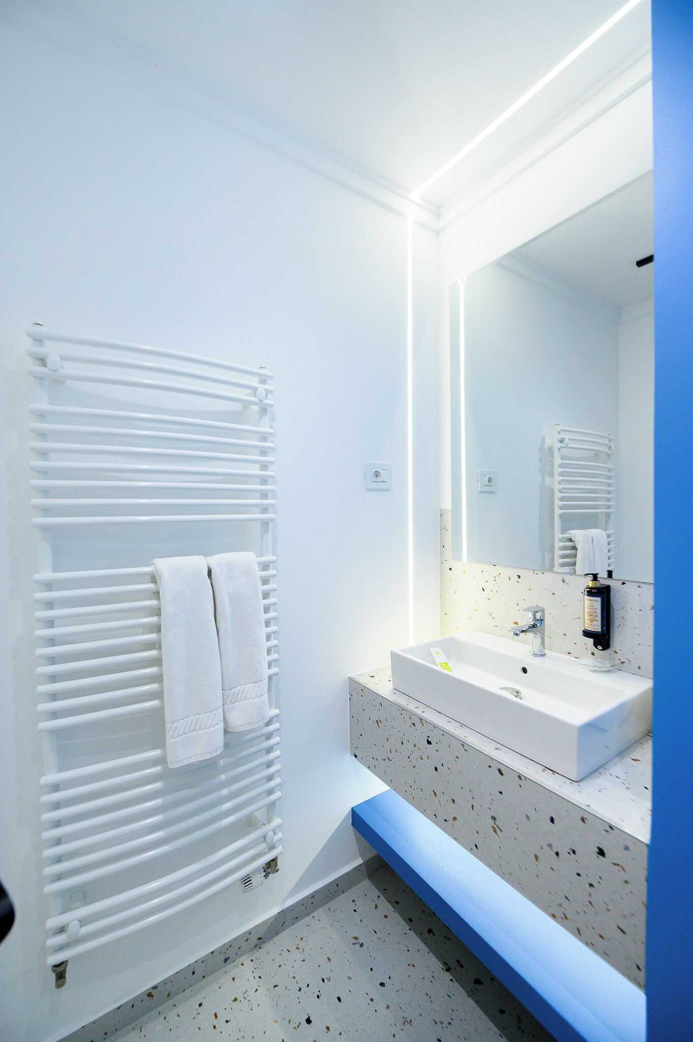 Een moderne badkamer met een witte radiator, een wastafel en een spiegel.