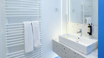A modern bathroom with a white radiator, a sink, and a mirror.