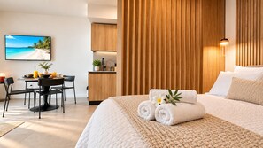 Habitación de hotel con cama, escritorio con productos de desayuno, vista a la playa y pared de madera.